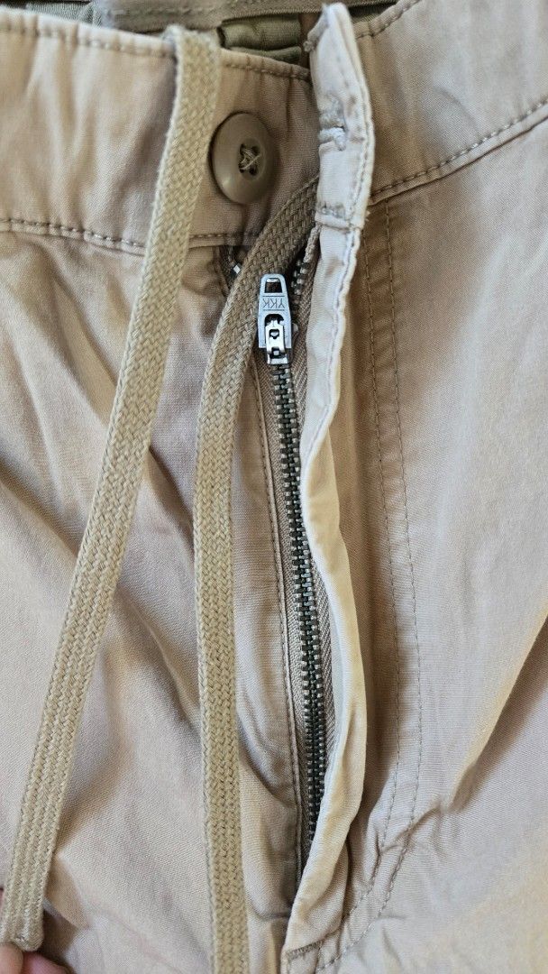 Uniqlo Beige Cargo Jogger Pants (Category: Joggers) located in General Trias. Submitted by gratsimaravilla (Listing ID 1470484276, Image 2). Description: Uniqlo beige cargo jogger pants in size M, fits waist 76-84cm. Made from 98% cotton and 2% spandex blend with some stretch. Features elastic waistband with drawstring, zippered fly with button closure, side cargo pockets, and elastic cuffs at the ankles. Note: tiny white paint marks on right leg