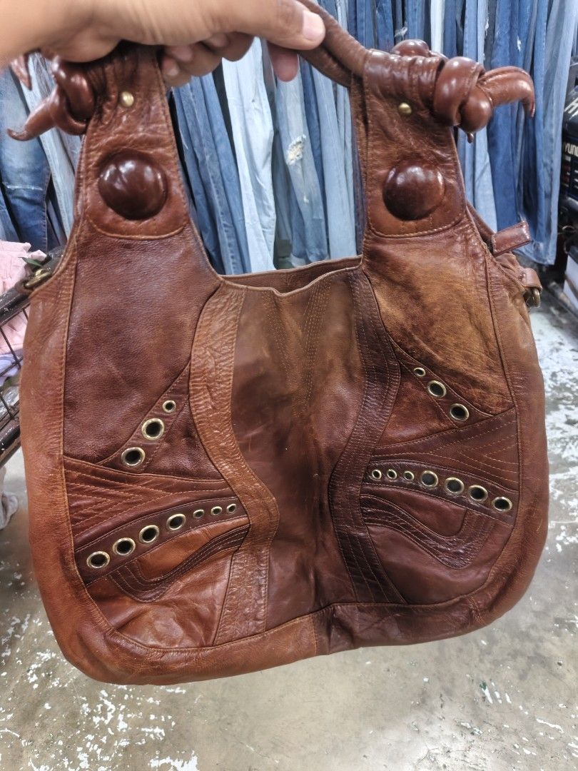 Vintage Brown Leather Patchwork Hobo Shoulder Bag with Eyelets (Category: Shoulder Bags) located in San Carlos City. Submitted by dhong_abay_thrift (Listing ID 1470351161, Image 2). Description: Brown leather shoulder bag. Patchwork construction with intricate stitching details, brass-tone eyelets, and wooden-look button accents on the front. Double structured handles with knot ties. Additional long adjustable strap attached on the sides. Back fe