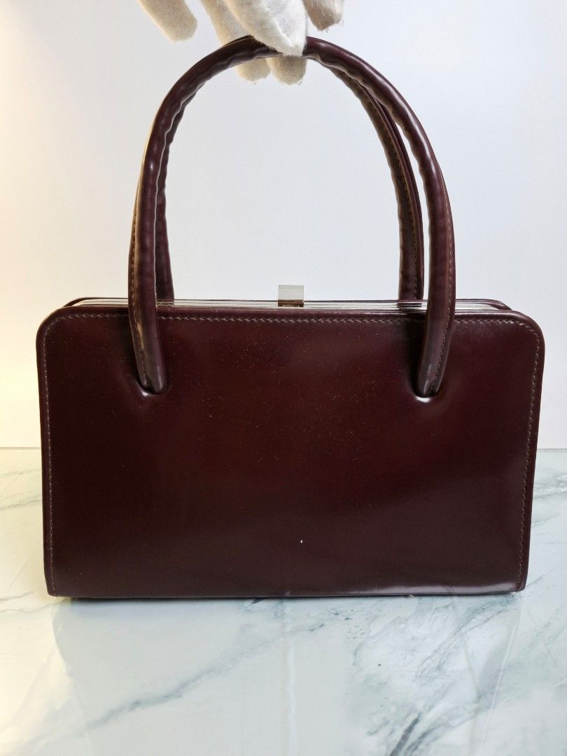 Vintage Burgundy Structured Handbag (Category: Shoulder Bags) located in Pasay City. Submitted by onick_79 (Listing ID 1470405764, Image 2). Description: - Dimensions: L 22.5 x H 14 x W 8 cm - Color: Deep burgundy - Material: Premium structured leather - Design: Classic retro style with a clean, rigid rectangular silhouette - Handles: Comfortable double rolled top handles - Closure: Secure metal frame with a top latch mechanism - Interior: Simple