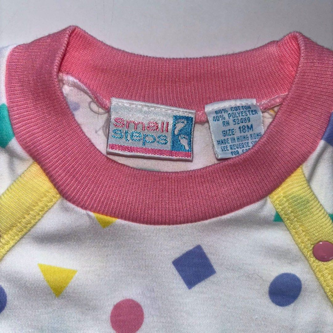 Vintage Small Steps Geometric Print Romper 18 Months (Category: Babies & Kids Fashion) located in Manila. Submitted by miamoire (Listing ID 1470556623, Image 2). Description: - Brand: Small Steps - Size: 18 months - Material: 60% cotton, 40% polyester blend (Made in Hong Kong) - Design: White fabric with colorful geometric shapes (circles, squares, triangles) - Details: Pink ribbed collar/cuffs, yellow shoulder trim, and snap button closures on t