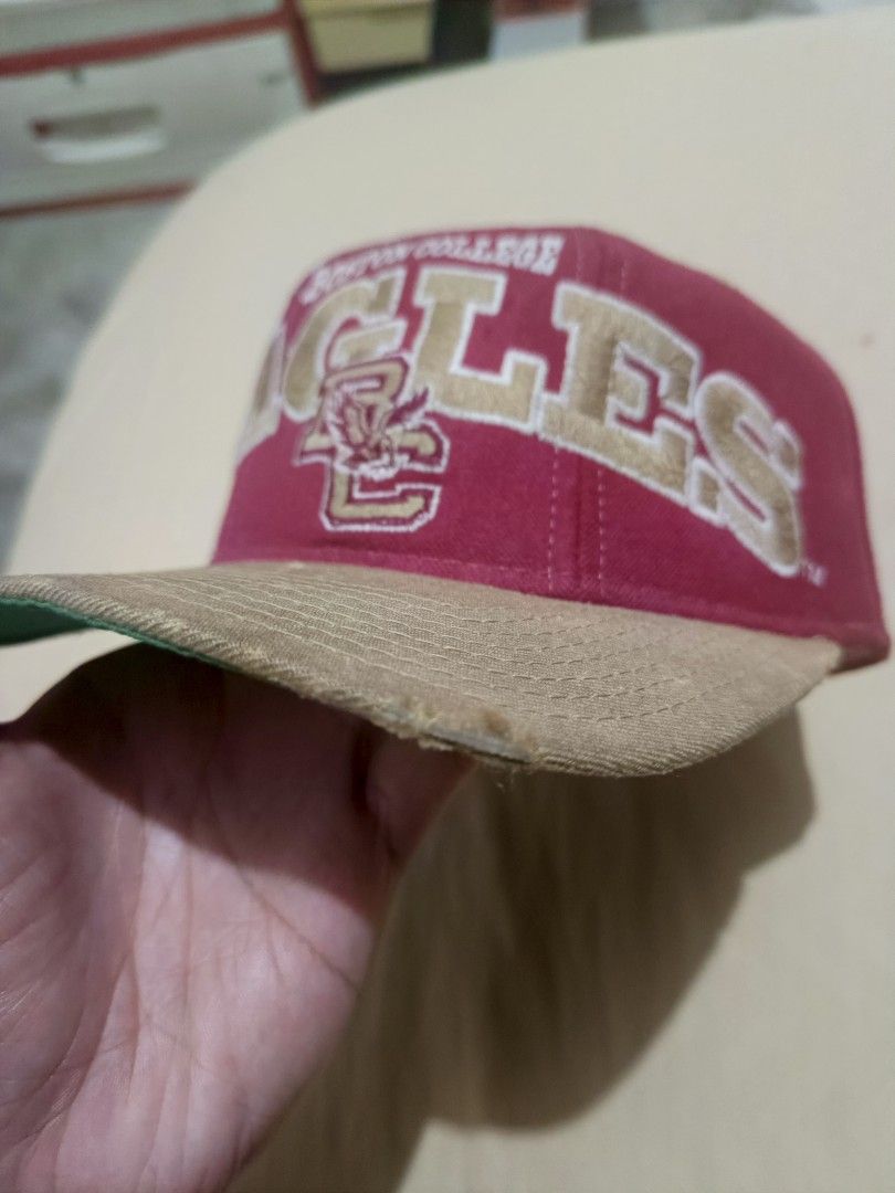 Vintage Starter Boston College Eagles Snapback Cap (Category: Caps & Hats) located in Jaen. Submitted by ratbunizer (Listing ID 1470394466, Image 3). Description: - Brand: Starter (official tags included) - Team: Boston College Eagles - Colorway: Red crown, tan brim, and green underbrim - Design: Large embroidered 'EAGLES' lettering and BC logo on the front - Closure: Adjustable snapback - Condition: Pre-owned with visible fraying and wear along 