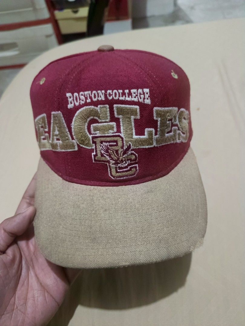 Vintage Starter Boston College Eagles Snapback Cap (Category: Caps & Hats) located in Jaen. Submitted by ratbunizer (Listing ID 1470394466, Image 1). Description: - Brand: Starter (official tags included) - Team: Boston College Eagles - Colorway: Red crown, tan brim, and green underbrim - Design: Large embroidered 'EAGLES' lettering and BC logo on the front - Closure: Adjustable snapback - Condition: Pre-owned with visible fraying and wear along 