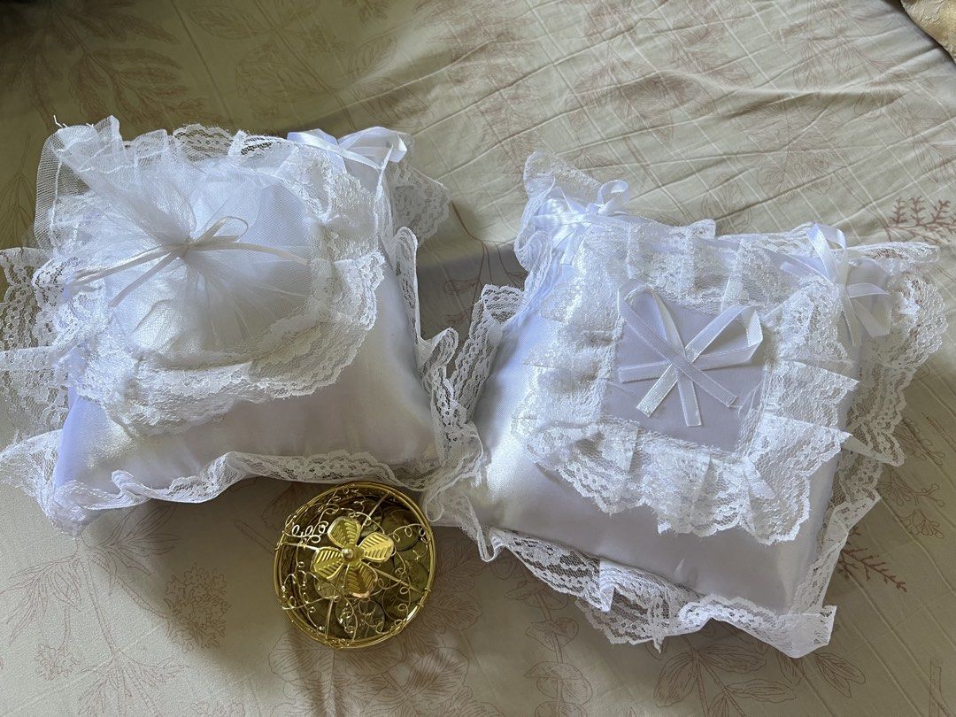 Wedding accessories, pillow and aras (Category: Accessory Holder, Box & Organizers) located in Cavite. Submitted by leley.light (Listing ID 1470382726, Image 1). Description: - Includes 2 white satin ring and aras pillows adorned with delicate lace, tulle ruffles, and ribbon accents - Comes with a small ornate gold-toned metal aras - Ideal set for wedding ceremonies, engagements, or ring photography.
