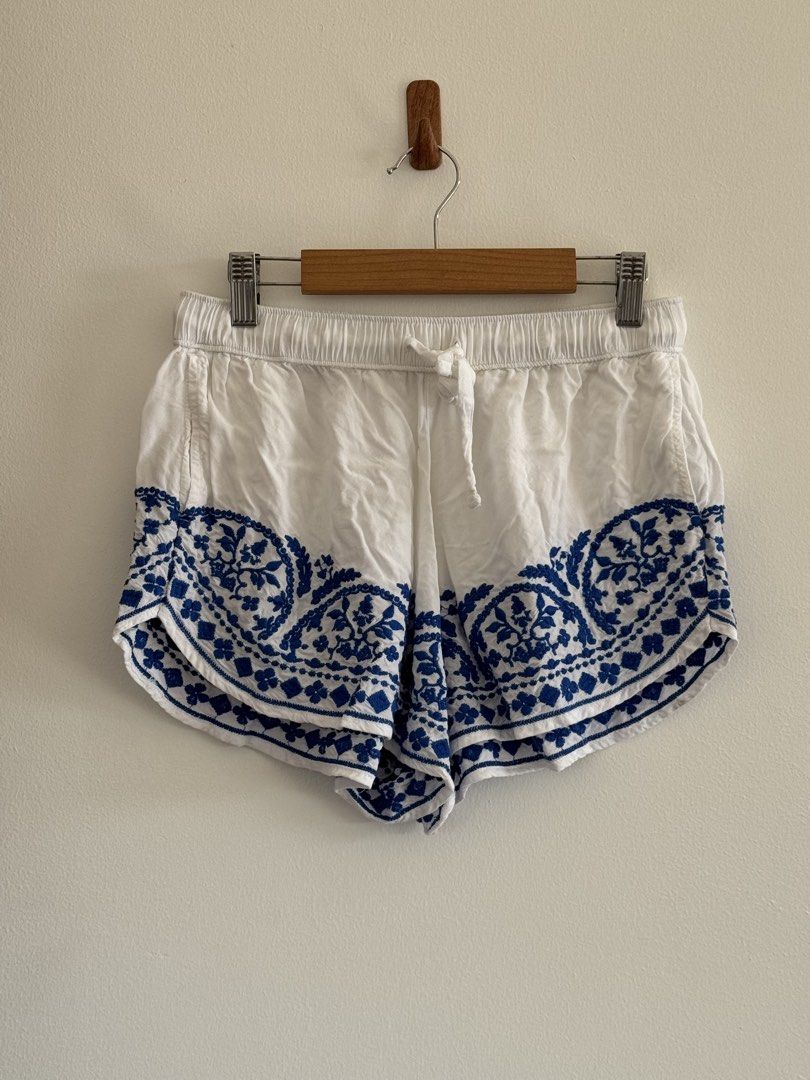 White and Blue Embroidered Shorts with Drawstring (Category: Shorts) located in Rizal. Submitted by mharieshine (Listing ID 1470452065, Image 2). Description: - Color: White with blue embroidered floral pattern - Material: Lightweight and breathable cotton - Fit: Relaxed fit with an elastic waistband and adjustable white drawstring - Design: Stylish curved hem with floral embroidery - Occasion: Ideal for casual summer outings, beach days, and war