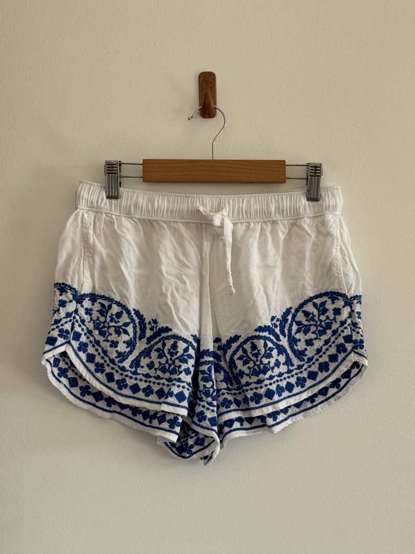 White and Blue Embroidered Shorts with Drawstring (Category: Shorts) located in Rizal. Submitted by mharieshine (Listing ID 1470452065, Image 1). Description: - Color: White with blue embroidered floral pattern - Material: Lightweight and breathable cotton - Fit: Relaxed fit with an elastic waistband and adjustable white drawstring - Design: Stylish curved hem with floral embroidery - Occasion: Ideal for casual summer outings, beach days, and war
