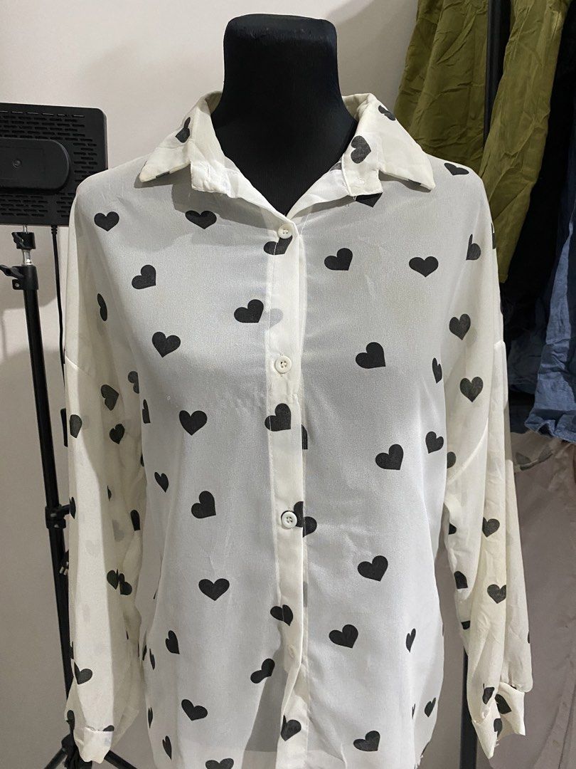 White button-down blouse with black heart print (Category: Blouses) located in Manila. Submitted by mpt99876 (Listing ID 1470497117, Image 3). Description: - Design: White button-down shirt with a playful black heart print - Fit: Relaxed and lightweight for comfortable all-day wear - Details: Classic collar neckline, long sleeves with button cuffs, and standard front button closure - Styling: Easily pairs with denim or skirts for a cute daily loo