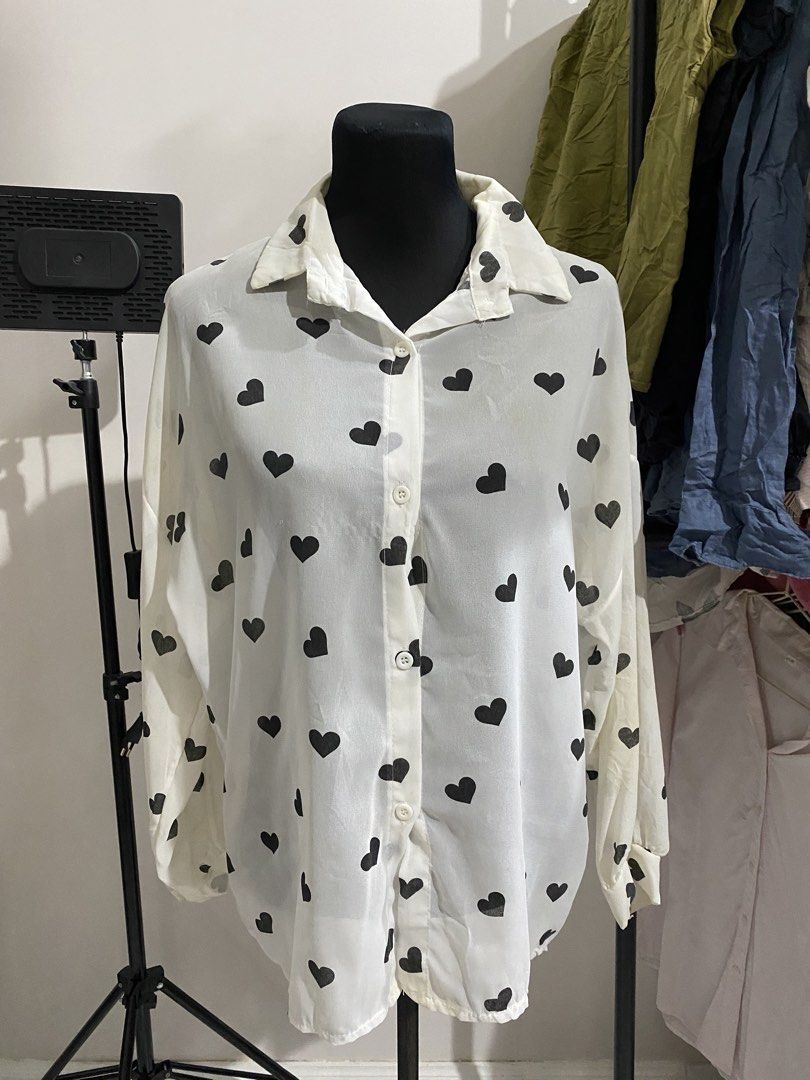 White button-down blouse with black heart print (Category: Blouses) located in Manila. Submitted by mpt99876 (Listing ID 1470497117, Image 1). Description: - Design: White button-down shirt with a playful black heart print - Fit: Relaxed and lightweight for comfortable all-day wear - Details: Classic collar neckline, long sleeves with button cuffs, and standard front button closure - Styling: Easily pairs with denim or skirts for a cute daily loo
