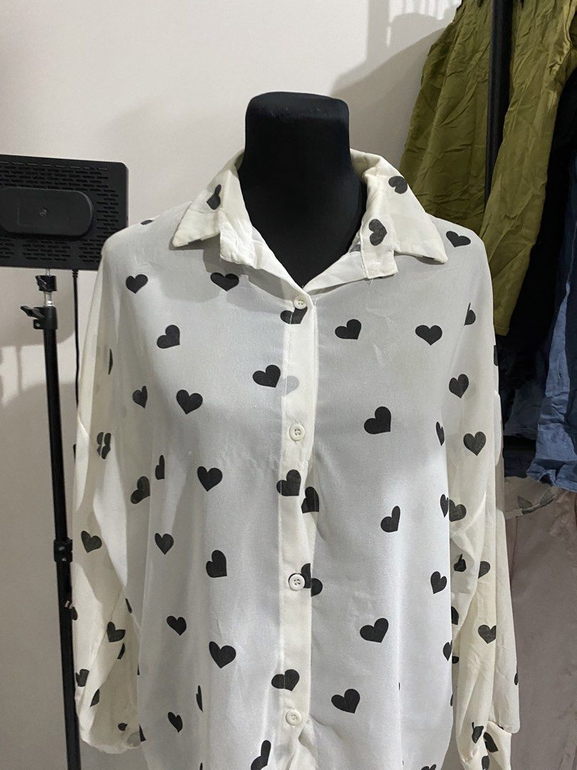 White button-down blouse with black heart print (Category: Blouses) located in Manila. Submitted by mpt99876 (Listing ID 1470497117, Image 2). Description: - Design: White button-down shirt with a playful black heart print - Fit: Relaxed and lightweight for comfortable all-day wear - Details: Classic collar neckline, long sleeves with button cuffs, and standard front button closure - Styling: Easily pairs with denim or skirts for a cute daily loo