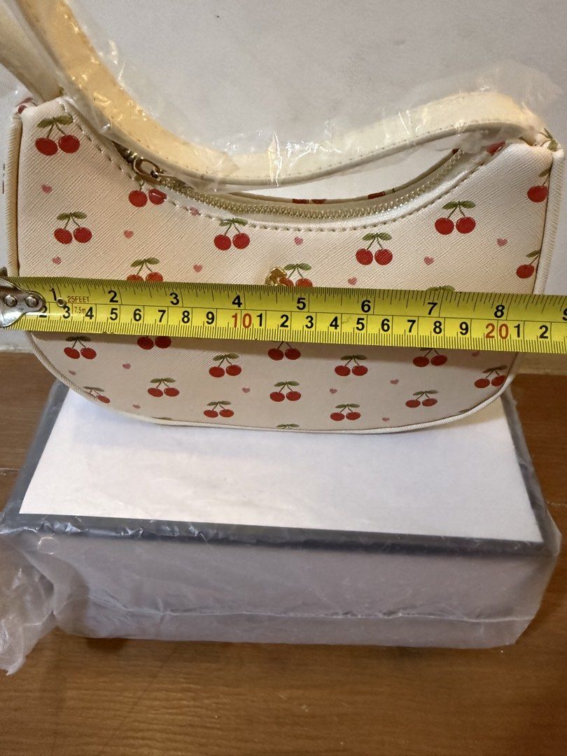 White Cherry Print Shoulder Bag (Category: Shoulder Bags) located in Bulacan. Submitted by emjay_17 (Listing ID 1470426680, Image 3). Description: - Style: White shoulder bag with red cherry and tiny pink heart all-over print - Condition: Brand new, never used, with plastic wrapping still on the strap - Dimensions: Roughly 20cm (across) x 15cm (down) - Hardware & Closure: Secure top zipper closure with gold-tone hardware - Storage: Comes stuffed 