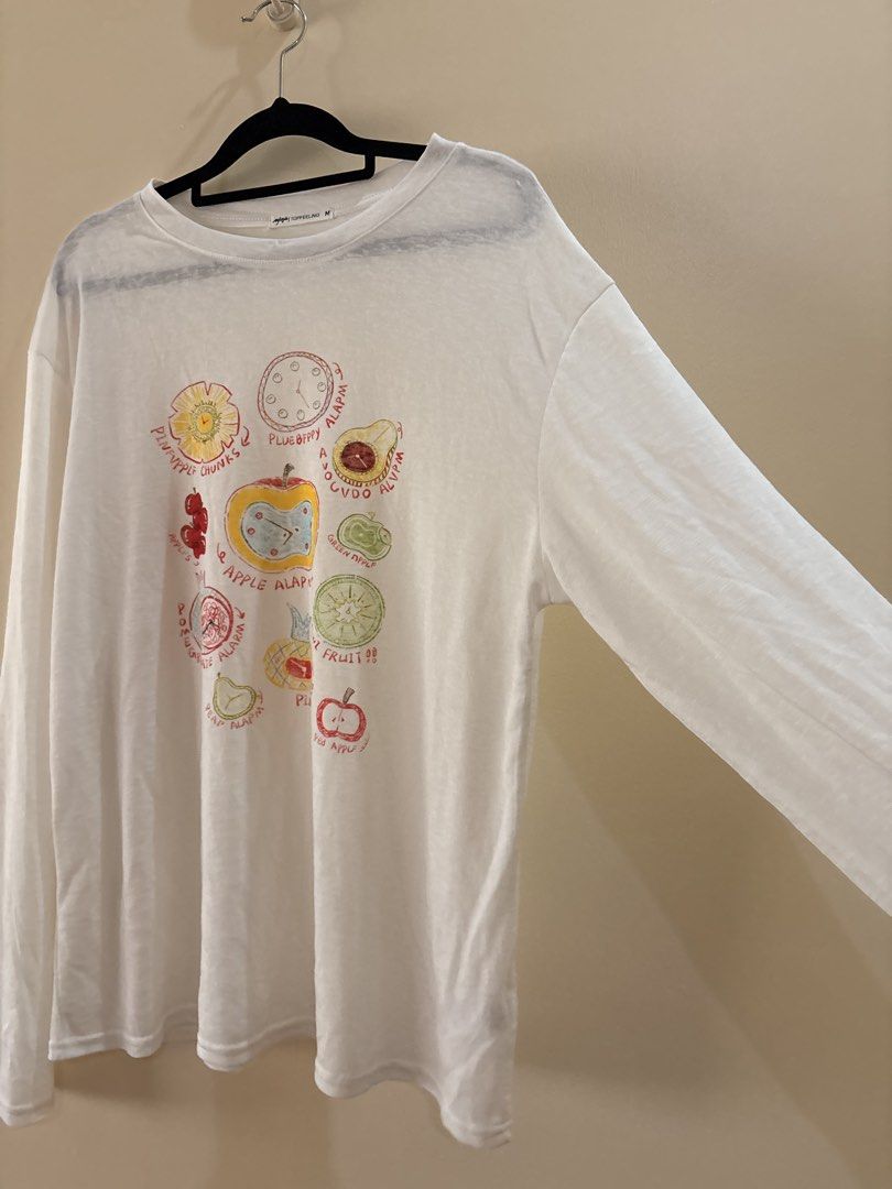 White Long Sleeve Fruit Graphic shirt (Category: Longsleeves) located in Manila. Submitted by anabri (Listing ID 1470371849, Image 2). Description: - Brand: TOPFEELING - Size: M can fit up to L - loose fit - Style: Long sleeve crew neck top - Design: Quirky fruit & clock graphics with playful misspelled text ("PLUEBFPPY ALAPM") - Fabric: Lightweight, semi-sheer with a bit of stretch - Condition: Great casual piece, ready to wear - LAST 2 PHOTOS F