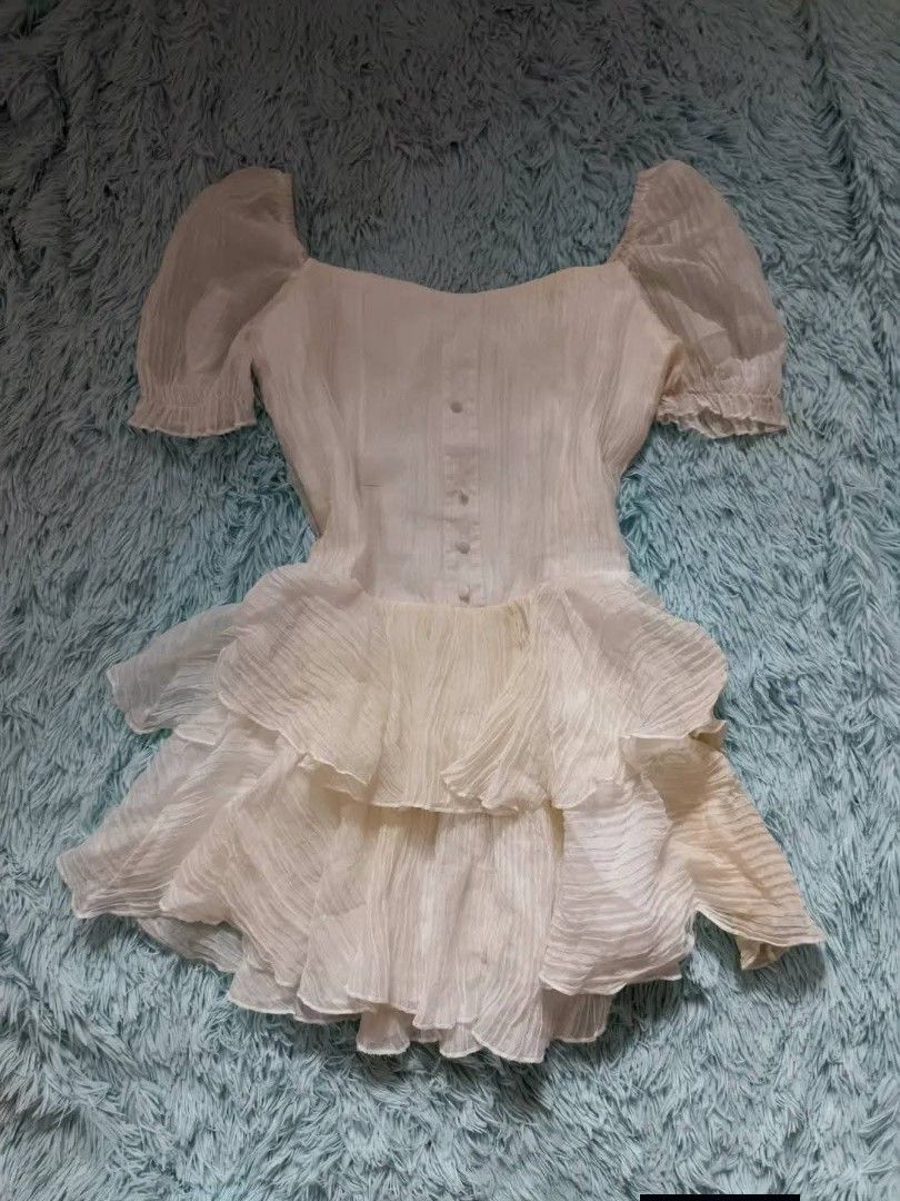 White ruffle mini dress short sleeve (Category: Dresses) located in Quezon City. Submitted by alluring.avenue (Listing ID 1470549326, Image 1). Description: - Color: White - Style: Mini dress with layered ruffled skirt - Neckline: Square neckline - Sleeves: Short puff sleeves with elastic cuffs - Details: Front button closure, lightweight textured fabric - Length: Above the knee - Versatility: Perfect for parties and casual outings; easy to style