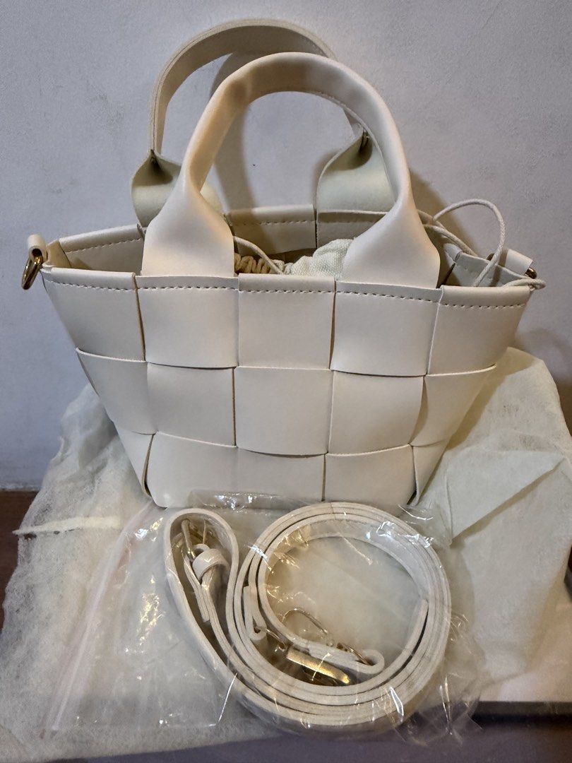 White Woven Leather Bucket Bag with Strap (Category: Shoulder Bags) located in Bulacan. Submitted by emjay_17 (Listing ID 1470408159, Image 2). Description: - Color & Material: White woven faux leather - Design: Structured checkerboard pattern - Features: Top handles and a secure drawstring inner pouch - Strap: Includes an adjustable, detachable matching white shoulder strap (still wrapped in plastic) - Condition: Brand new, never used, with a pe
