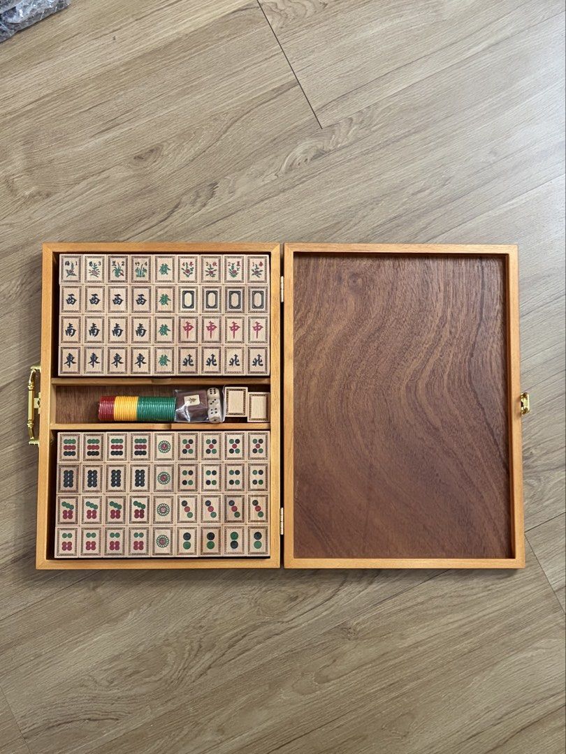 Wooden Mahjong Set With Storage Case (Category: Board Games & Puzzles) located in Valenzuela. Submitted by allgoodstyo (Listing ID 1470351139, Image 2). Description: - Complete mahjong set with wooden tiles, counting chips, dice, and spare tiles - Housed in a sturdy wooden carrying case with brass-toned latches and hinges - Lid features detailed engraved artwork of figures in a landscape with Chinese characters - Clean wooden surfaces throughout 