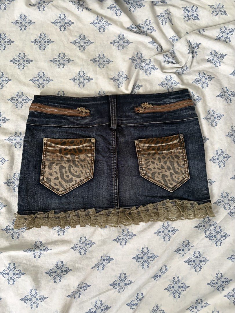 Y2K Leopard Denim Ruffle Mini Skirt Size M (Category: Skirts) located in Angeles City. Submitted by charishurb08031 (Listing ID 1470430170, Image 2). Description: - Size: 29-30 (with inner drawstring waistband) Length: 12 - Design: Dark wash denim with brown leopard print panels and rhinestone front graphic - Details: Decorative zippers and functional back pockets - Hem: Cute light brown lace ruffle trim.