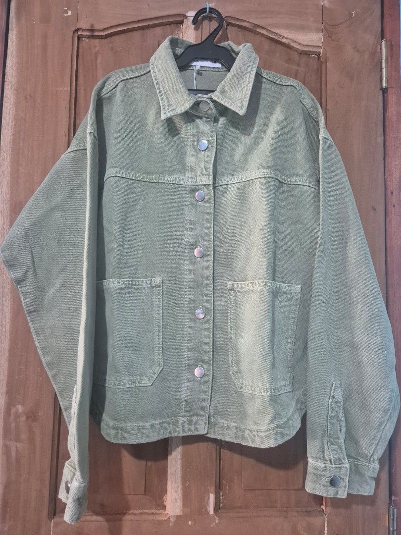 Zara Green Denim Jacket (Category: Coats, Jackets and Outerwear) located in Makati City. Submitted by neri_11 (Listing ID 1470419940, Image 2). Description: - Brand: Zara - Color: Trendy sage green - Condition: Brand new with original hang tag attached (includes a minor spot near the back yoke seam) - Details: Button-up front, metallic hardware, two chest pockets, long sleeves with button cuffs - Perfect layering piece for any casual outfit .