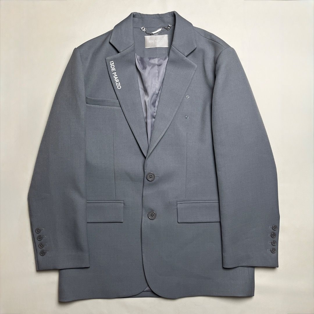 13DE MARZO Grey Blazer Jacket (Category: Coats, Jackets and Outerwear) located in Caloocan City. Submitted by achilles_grails (Listing ID 1470583818, Image 1). Description: - Brand: 13DE MARZO - Color: Grey - Fit: Structured shoulders with a two-button front closure - Details: Branded text printed on the right lapel, silver-tone chain detail near the collar tag - Pockets: Flap pockets at the waist - Cuffs: Four buttons on each cuff - Interior: Fu