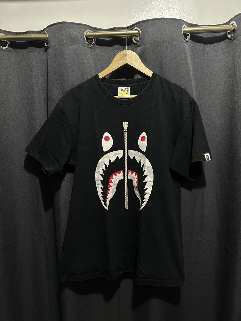 A Bathing Ape (BAPE) Shark Full-Zip Graphic Tee (Category: Tshirts & Polo Shirts ) located in Buenavista. Submitted by themodernrack (Listing ID 1470599126, Image 1). Description: Condition: Good Condition/Minimal Hairlines Measurements & Sizing: Size: Tagged Size XL (BAPE regular/classic fit; fits like Men’s L/XL) Width (Pit to Pit): 22” Length: 29”.