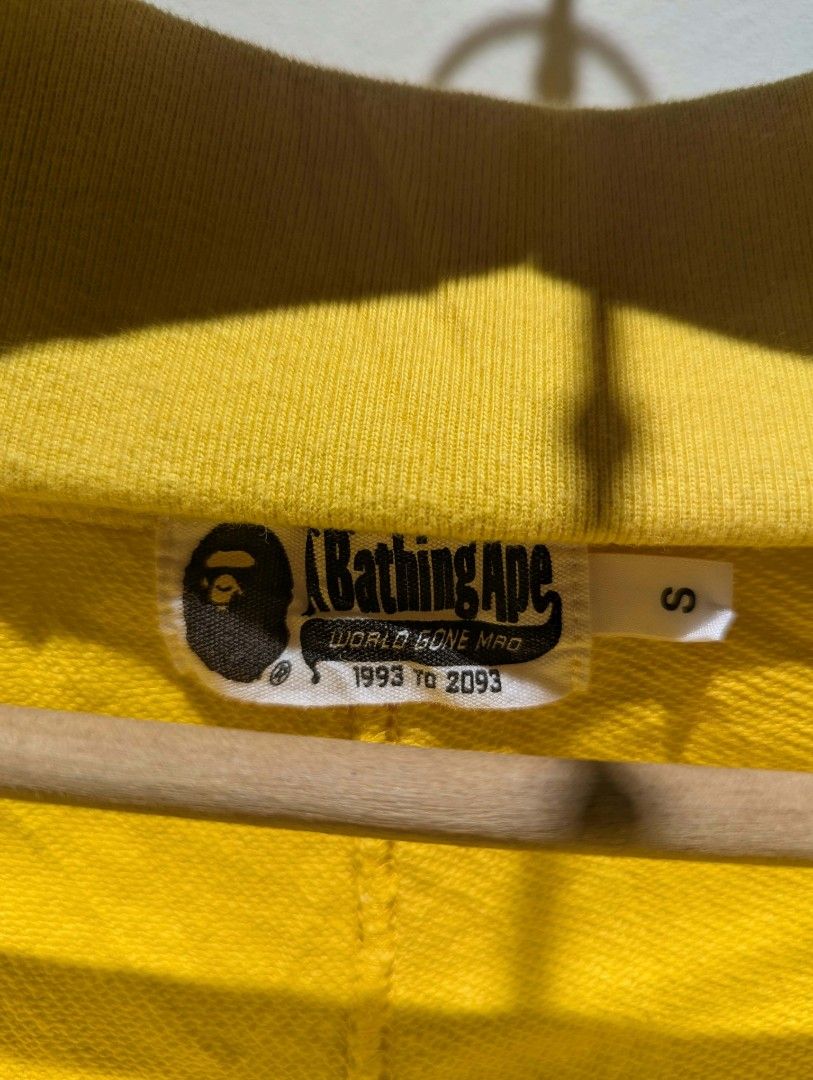 A Bathing Ape BAPE Shark Shorts Yellow (Category: Shorts) located in Manila. Submitted by grandwater.53a8ce (Listing ID 1470680324, Image 2). Description: - Brand: A Bathing Ape (BAPE) - Item: Shark Face Sweatshorts - Color: Bright Yellow - Size: Small - Details: Iconic front shark graphic, drawstring waistband, blue and white striped hem - Authenticity: Includes internal brand tag and gold ape head tag.
