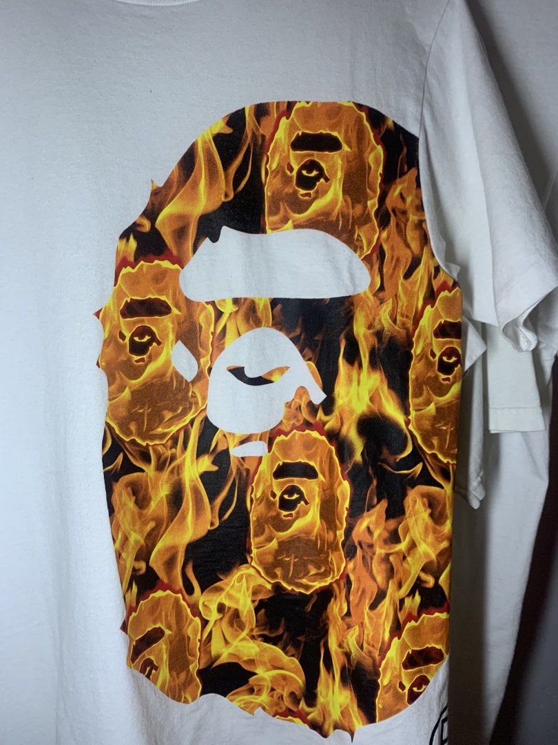 A Bathing Ape Fire Camo Ape Head T-shirt (Category: Tshirts & Polo Shirts ) located in Manila. Submitted by lstrthriftv1 (Listing ID 1470617683, Image 2). Description: - Brand: Bape - Item: Flaming Ape Head Tee - Color: White with vibrant fire print - Size: Small - Material: 100% cotton (Made in China) - Condition: Clean fabric, classic neck and sleeve tags intact - Ideal for streetwear styling.