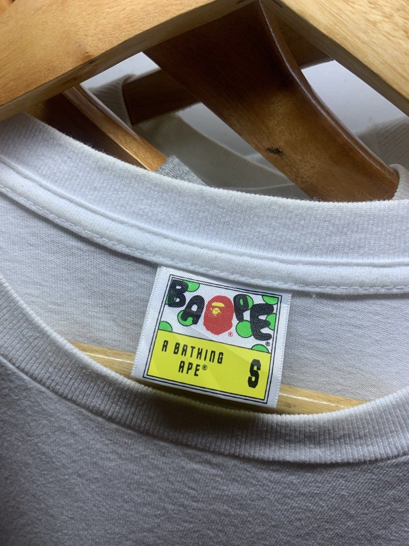 A Bathing Ape Fire Camo Ape Head T-shirt (Category: Tshirts & Polo Shirts ) located in Manila. Submitted by lstrthriftv1 (Listing ID 1470617683, Image 3). Description: - Brand: Bape - Item: Flaming Ape Head Tee - Color: White with vibrant fire print - Size: Small - Material: 100% cotton (Made in China) - Condition: Clean fabric, classic neck and sleeve tags intact - Ideal for streetwear styling.