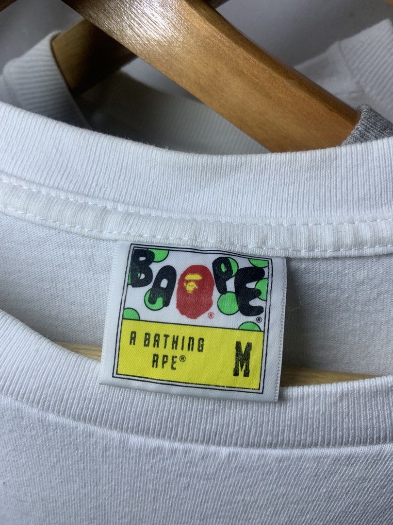 A Bathing Ape x Star Wars Bape Tee White Size M (Category: Tshirts & Polo Shirts ) located in Manila. Submitted by lstrthriftv1 (Listing ID 1470617506, Image 2). Description: - Brand: A Bathing Ape (BAPE) x Star Wars - Design: Baby Milo with BB-8 and droid graphic on front chest - Size: Medium (Yellow collar tag) - Material: 100% Cotton (Made in China) - Details: Classic crewneck, short sleeves, and signature sleeve ape tag near hem - Condition: 
