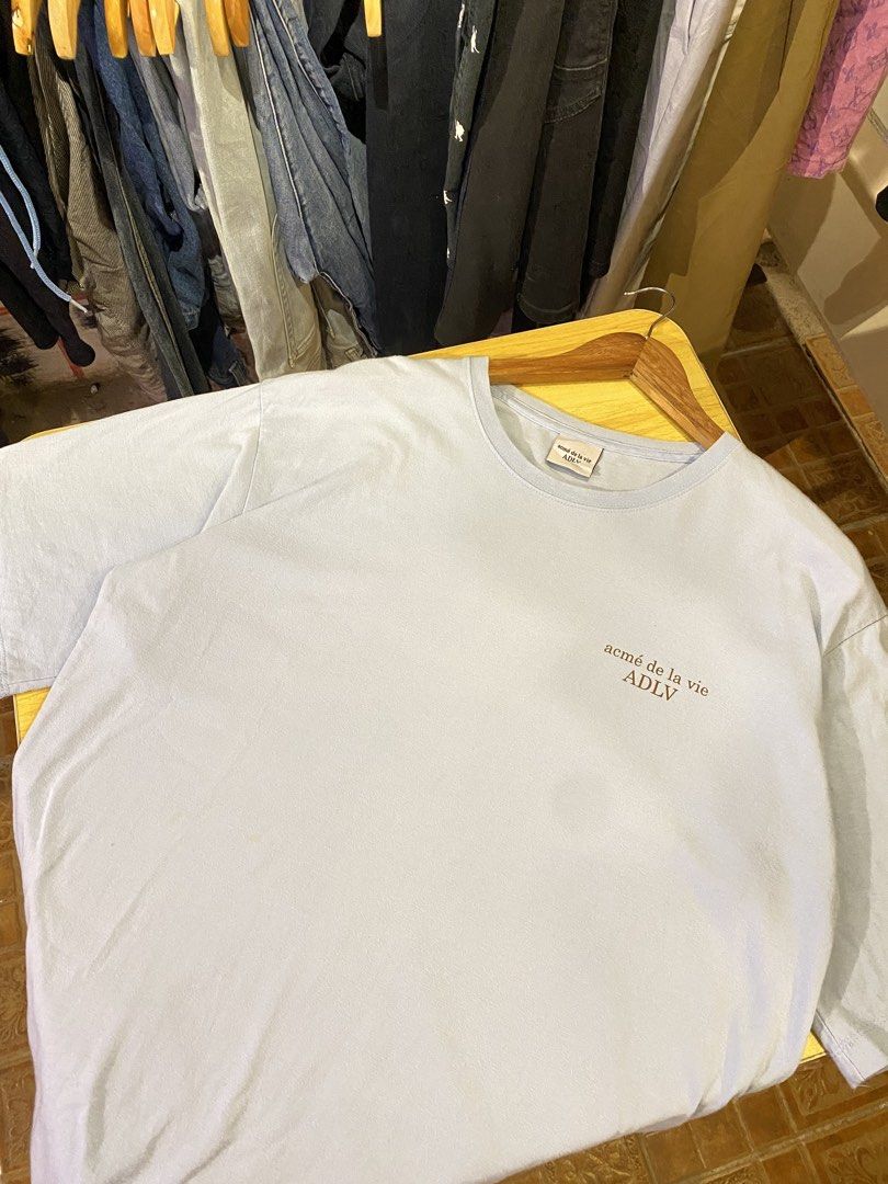 acmé de la vie ( ADLV) Size 1 (Category: Tshirts & Polo Shirts ) located in Manila. Submitted by thriftvibes324 (Listing ID 1470696024, Image 1). Description: - Brand: acmé de la vie (ADLV) - Color: Light Blue - Size: 1 (Relaxed fit) - Design: Small brown front chest print and large matching back print - Details: Classic crew neck, super soft and comfortable fabric.