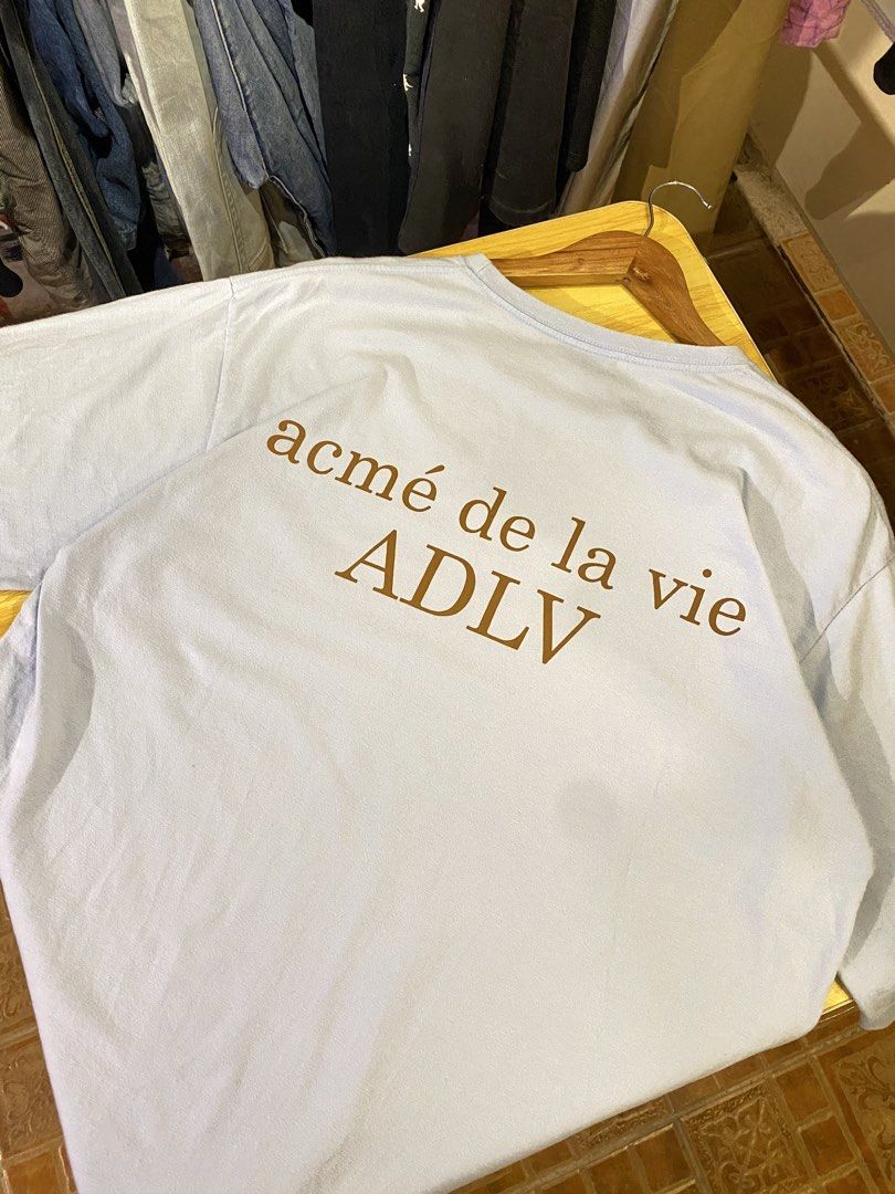 acmé de la vie ( ADLV) Size 1 (Category: Tshirts & Polo Shirts ) located in Manila. Submitted by thriftvibes324 (Listing ID 1470696024, Image 2). Description: - Brand: acmé de la vie (ADLV) - Color: Light Blue - Size: 1 (Relaxed fit) - Design: Small brown front chest print and large matching back print - Details: Classic crew neck, super soft and comfortable fabric.