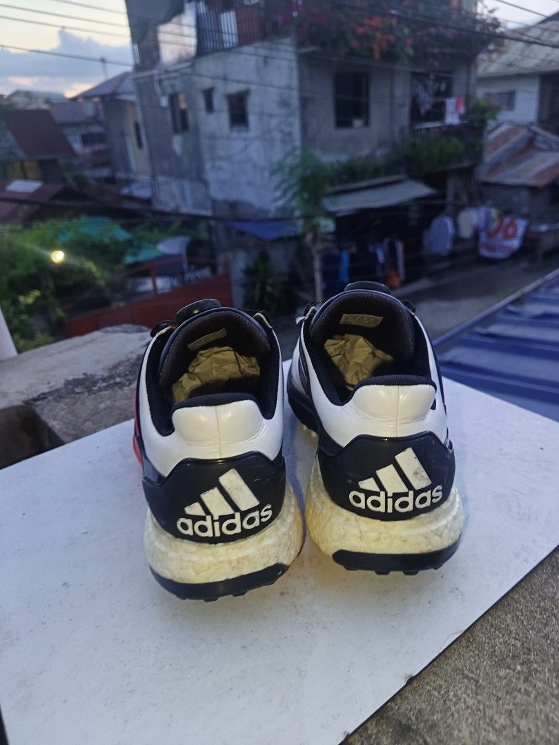 Adidas Boost Golf Shoes with Boa Lacing System (Category: Golf) located in Davao. Submitted by judethrifter (Listing ID 1470689836, Image 3). Description: - Brand: Adidas Golf - Colorway: White, black, and red with stylish pink accent stripes - Closure: Boa dial lacing system for quick and secure adjustments - Cushioning: Visible Boost midsole with 'boost endless energy' printed insoles - Soles: Removable spiked soles featuring a red and white gr