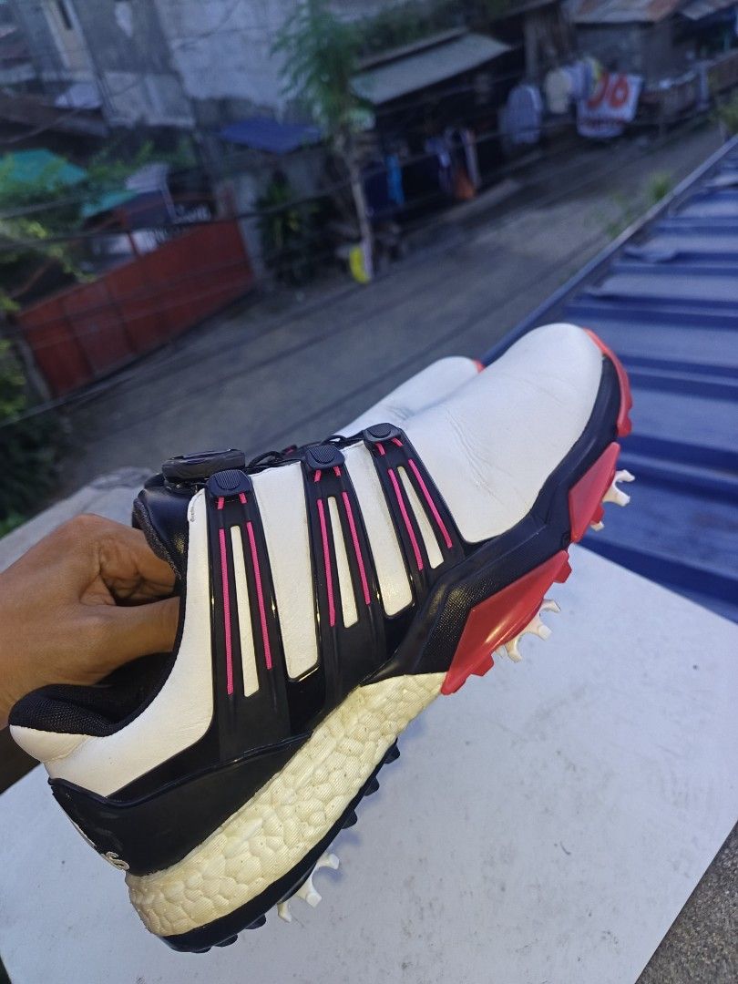 Adidas Boost Golf Shoes with Boa Lacing System (Category: Golf) located in Davao. Submitted by judethrifter (Listing ID 1470689836, Image 2). Description: - Brand: Adidas Golf - Colorway: White, black, and red with stylish pink accent stripes - Closure: Boa dial lacing system for quick and secure adjustments - Cushioning: Visible Boost midsole with 'boost endless energy' printed insoles - Soles: Removable spiked soles featuring a red and white gr