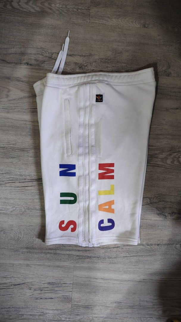 Adidas Pharrell Williams Hu Sun Calm Shorts (Category: Shorts) located in Quezon City. Submitted by truedeer_cda94c (Listing ID 1470602562, Image 3). Description: - Authentic Adidas Pharrell Williams collection - Color: Crisp white with multi-color details - Design: 'SUN' and 'CALM' text on legs, Hu triangle logo on back - Storage: Secure side zip pockets with adjustable drawstring waistband - Details: Colorful embroidered Adidas trefoil tag - Ma