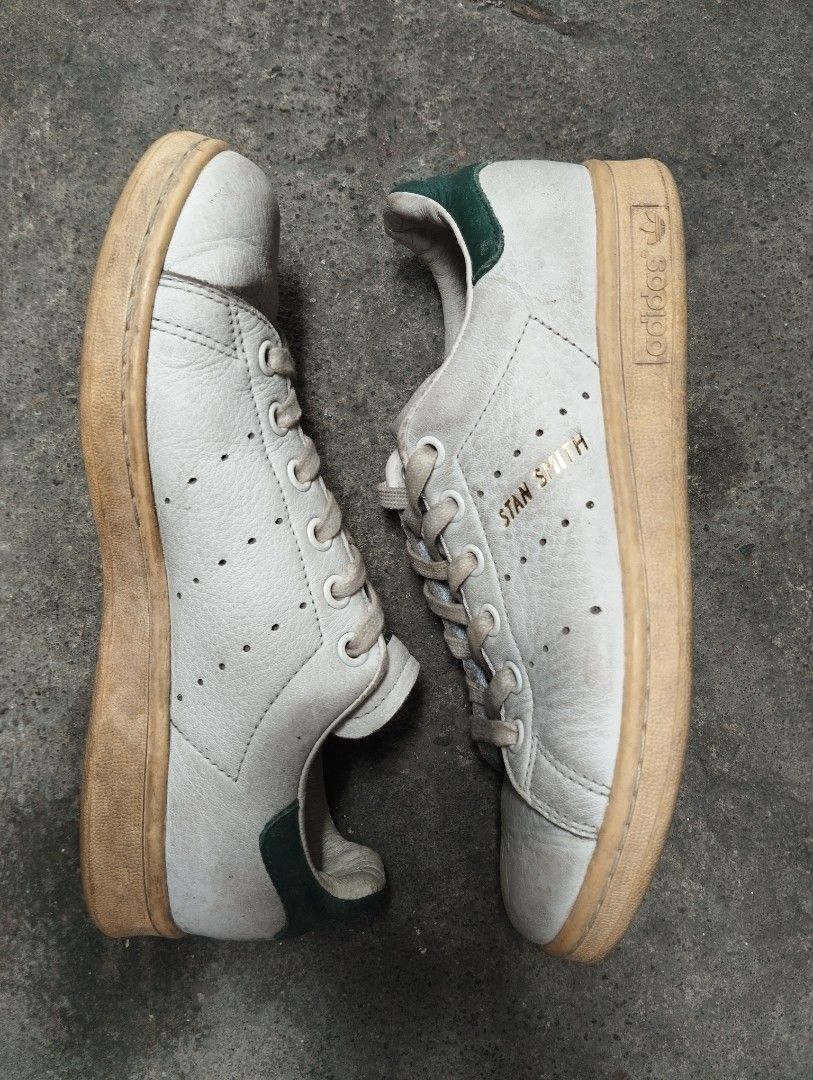 Adidas Stan Smith White Green Sneakers (Category: Sneakers) located in Manila. Submitted by cosmictree_1321 (Listing ID 1470598573, Image 2). Description: Classic Adidas Stan Smith sneakers in white with green heel tabs. Iconic perforated three stripes on the sides with gold lettering. White laces included. Rubbers soles have normal dirt buildup from walking. Leather uppers show standard creasing and scuffs near the toe areas. Soles still have pl