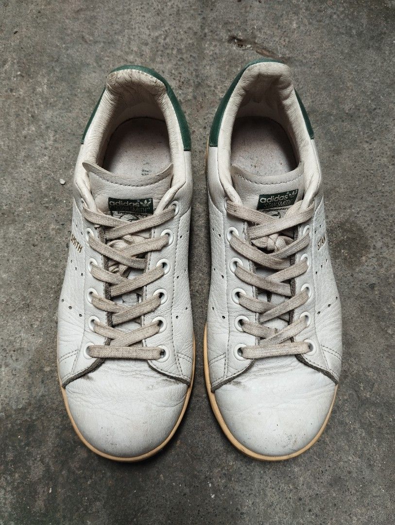 Adidas Stan Smith White Green Sneakers (Category: Sneakers) located in Manila. Submitted by cosmictree_1321 (Listing ID 1470598573, Image 1). Description: Classic Adidas Stan Smith sneakers in white with green heel tabs. Iconic perforated three stripes on the sides with gold lettering. White laces included. Rubbers soles have normal dirt buildup from walking. Leather uppers show standard creasing and scuffs near the toe areas. Soles still have pl