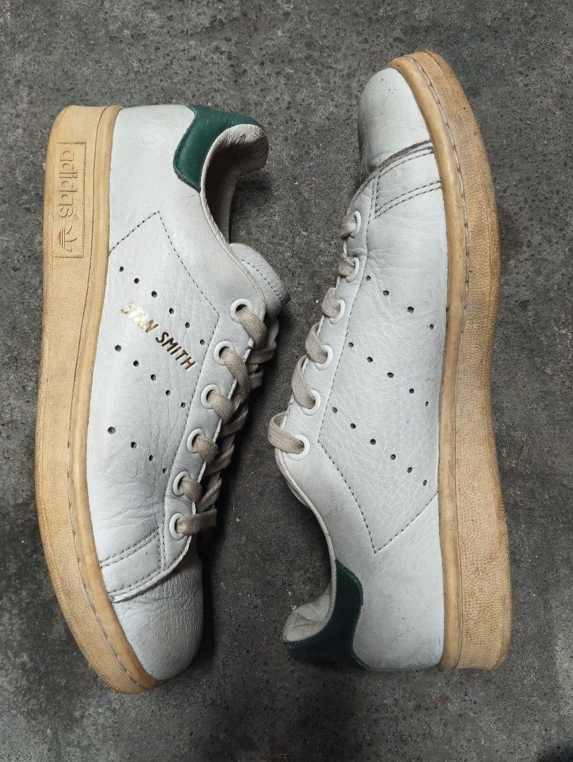 Adidas Stan Smith White Green Sneakers (Category: Sneakers) located in Manila. Submitted by cosmictree_1321 (Listing ID 1470598573, Image 3). Description: Classic Adidas Stan Smith sneakers in white with green heel tabs. Iconic perforated three stripes on the sides with gold lettering. White laces included. Rubbers soles have normal dirt buildup from walking. Leather uppers show standard creasing and scuffs near the toe areas. Soles still have pl