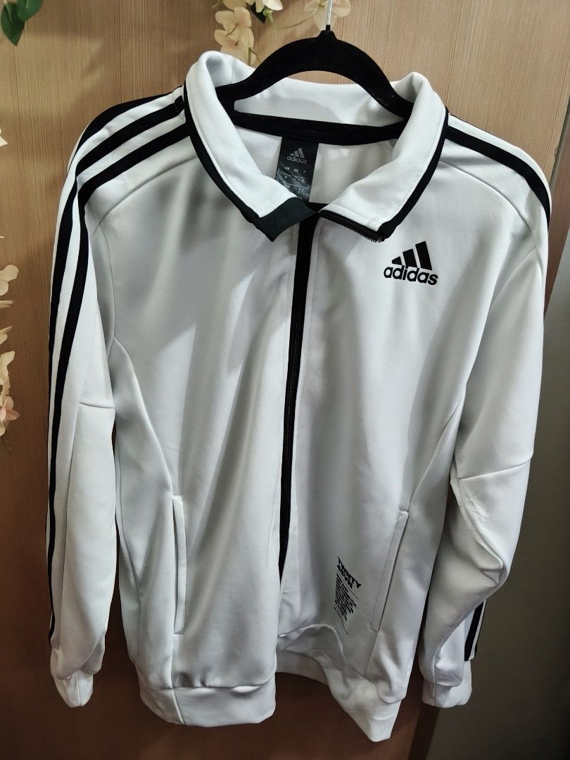 Adidas White Black 3-Stripes Track Jacket Size L (Category: Coats, Jackets and Outerwear) located in Quezon City. Submitted by queenbaby1819 (Listing ID 1470598057, Image 2). Description: - Brand: Adidas - Color: White with black 3-stripes and collar trim - Size: Large (tag at inner collar) - Features: Full zip closure, functional side pockets, graphic text near lower left hem - Origin: Made in Cambodia - Condition: Clean aesthetic, standard spor