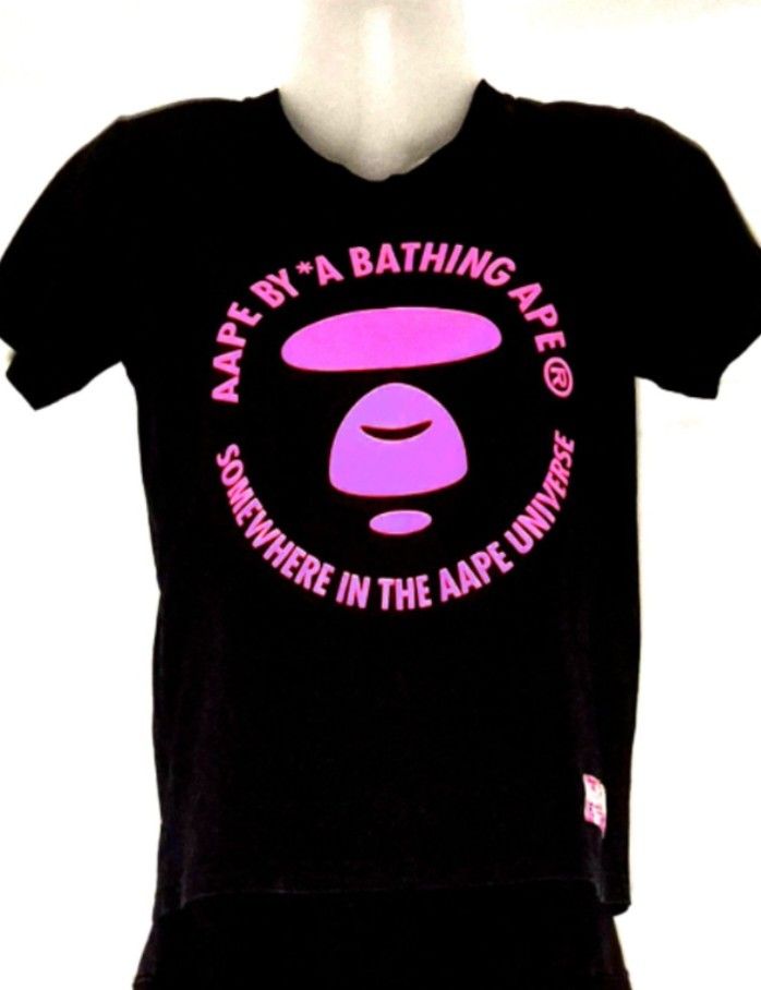 Authentic AAPE By A Bathing Ape "Moonface" Tee (Category: Shirts) located in Antipolo. Submitted by saribymonica (Listing ID 1470572996, Image 1). Description: Authentic AAPE By A Bathing Ape "Moonface" Tee Condition: Excellent preloved condition. The front pink graphic is flawless with no cracking or fading. Inner care tag has been cut, but all branding markers and security tags are perfectly intact (see photos). Authenticity: 100% Authentic. Fe