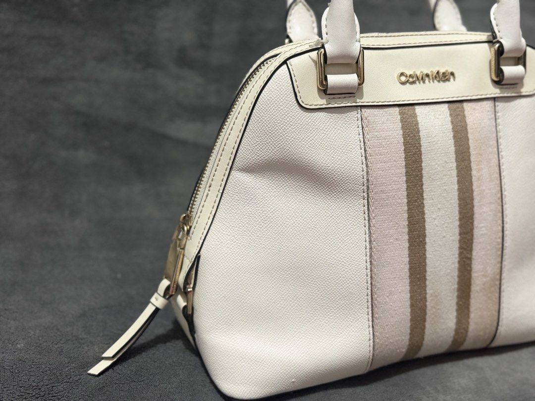Authentic Calvin Klein US Stripe Dome Satchel / Handbag (Category: Luxury Bags & Wallets) located in Mandaluyong City. Submitted by josa_xox0i8 (Listing ID 1470696015, Image 3). Description: ✨ AUTHENTIC CALVIN KLEIN STYLISH DOME SATCHEL BAG ✨ Bought directly from the US! Gorgeous neutral white/cream tone with signature webbing stripes and gold-tone hardware—perfect for everyday casual or work wear! 📌 DETAILS: Brand: Calvin Klein Condition: Unuse