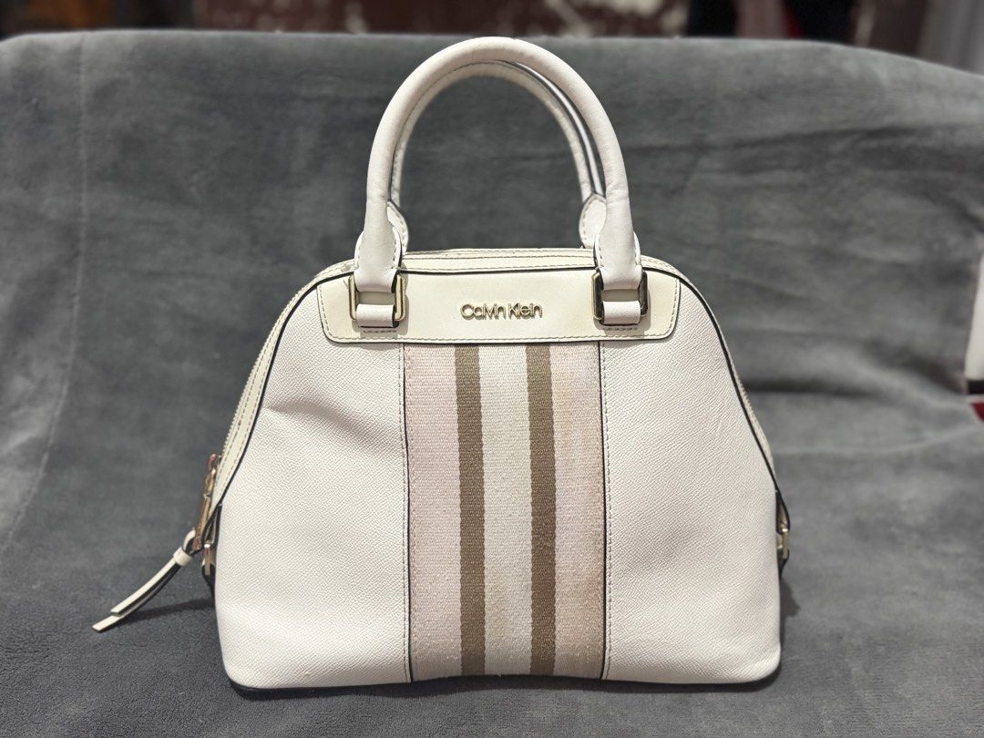 Authentic Calvin Klein US Stripe Dome Satchel / Handbag (Category: Luxury Bags & Wallets) located in Mandaluyong City. Submitted by josa_xox0i8 (Listing ID 1470696015, Image 2). Description: ✨ AUTHENTIC CALVIN KLEIN STYLISH DOME SATCHEL BAG ✨ Bought directly from the US! Gorgeous neutral white/cream tone with signature webbing stripes and gold-tone hardware—perfect for everyday casual or work wear! 📌 DETAILS: Brand: Calvin Klein Condition: Unuse