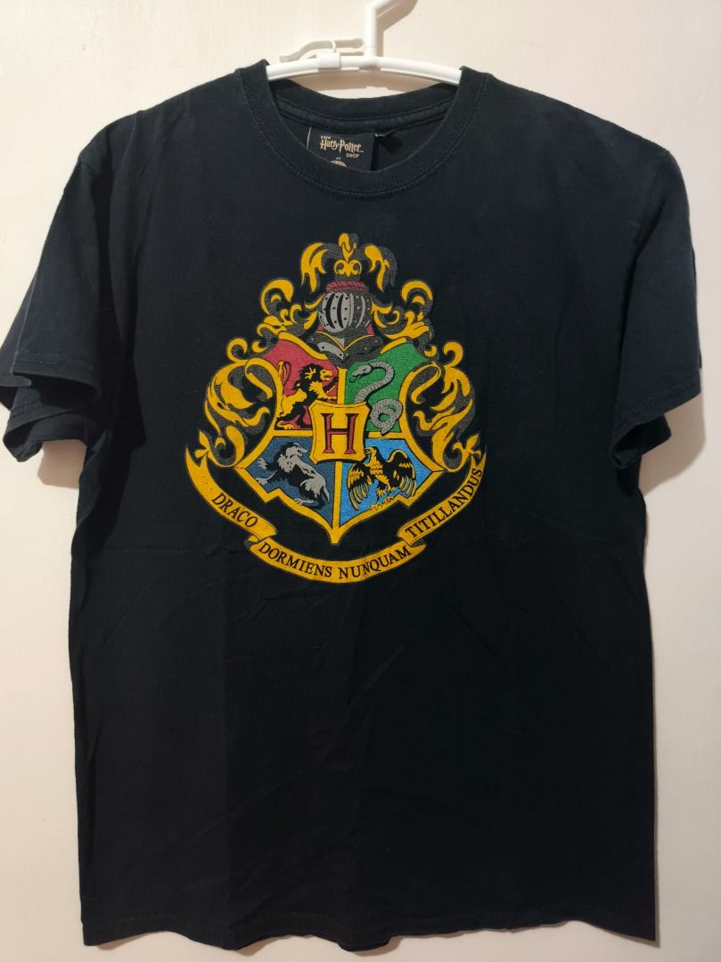 Authentic Harry Potter Hogwarts Crest Graphic Tee - Size Medium Black (Category: Tshirts & Polo Shirts ) located in San Leonardo. Submitted by burgossanleonardo.12345 (Listing ID 1470672935, Image 1). Description: • Brand: The Harry Potter Shop • Size: Medium (M) • Color: Black • Material: 100% Cotton (Soft and breathable fabric) • Condition: Pre-loved in great condition. No major stains, holes, or fading. Print is fully intact. Selling as is.
