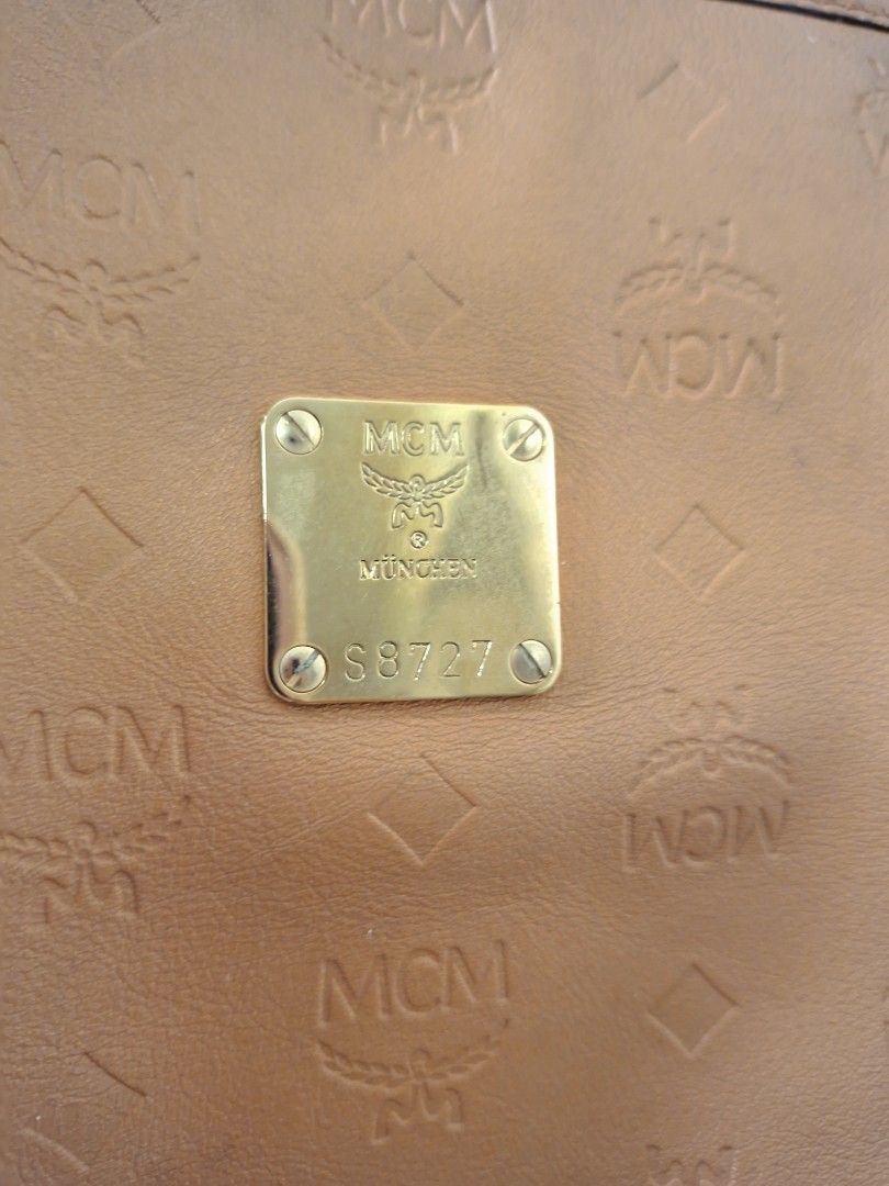 Authentic MCM Cognac Monogram Embossed Leather Tote Bag (Category: Tote Bags) located in Antipolo. Submitted by cheche2111 (Listing ID 1470561813, Image 2). Description: - Material: Premium tan leather with all-over embossed MCM monogram pattern - Hardware: Elegant gold-tone hardware with front metal plaque (stamped Munich and serial number S8727) - Closure: Secure zip-top closure - Straps: Comfortable double shoulder straps in matching tan leath