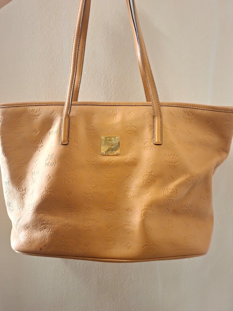 Authentic MCM Cognac Monogram Embossed Leather Tote Bag (Category: Tote Bags) located in Antipolo. Submitted by cheche2111 (Listing ID 1470561813, Image 1). Description: - Material: Premium tan leather with all-over embossed MCM monogram pattern - Hardware: Elegant gold-tone hardware with front metal plaque (stamped Munich and serial number S8727) - Closure: Secure zip-top closure - Straps: Comfortable double shoulder straps in matching tan leath