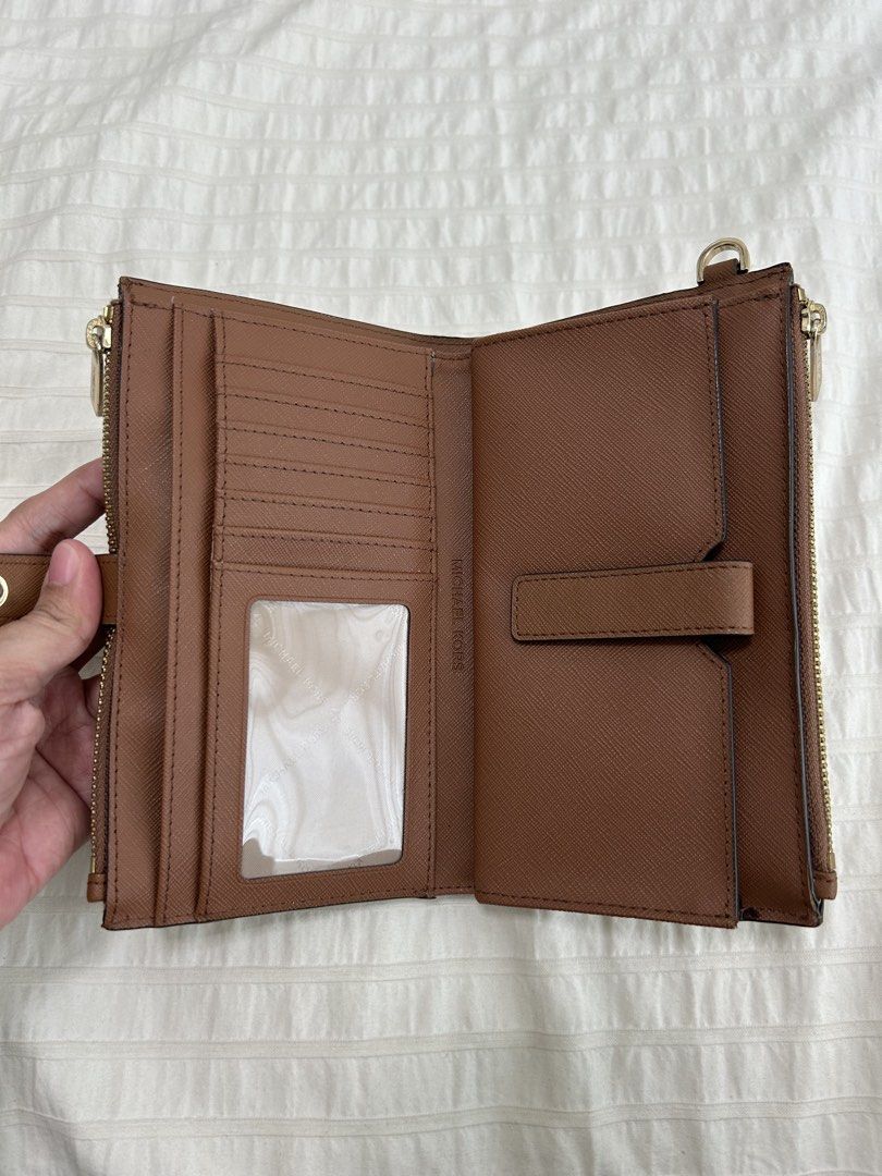 Authentic Michael Kors Jet Set Wallet ❤️ (Category: Wallets & Card holders) located in Taguig. Submitted by luckythriftph (Listing ID 1470586094, Image 2). Description: Selling my Michael Kors wallet in a beautiful, classic brown color with gold-tone hardware. ✨ Details: * Saffiano-textured leather * Elegant gold Michael Kors logo * Multiple card slots and ID window * Two zippered compartments * Spacious compartments for cash, receipts, and other
