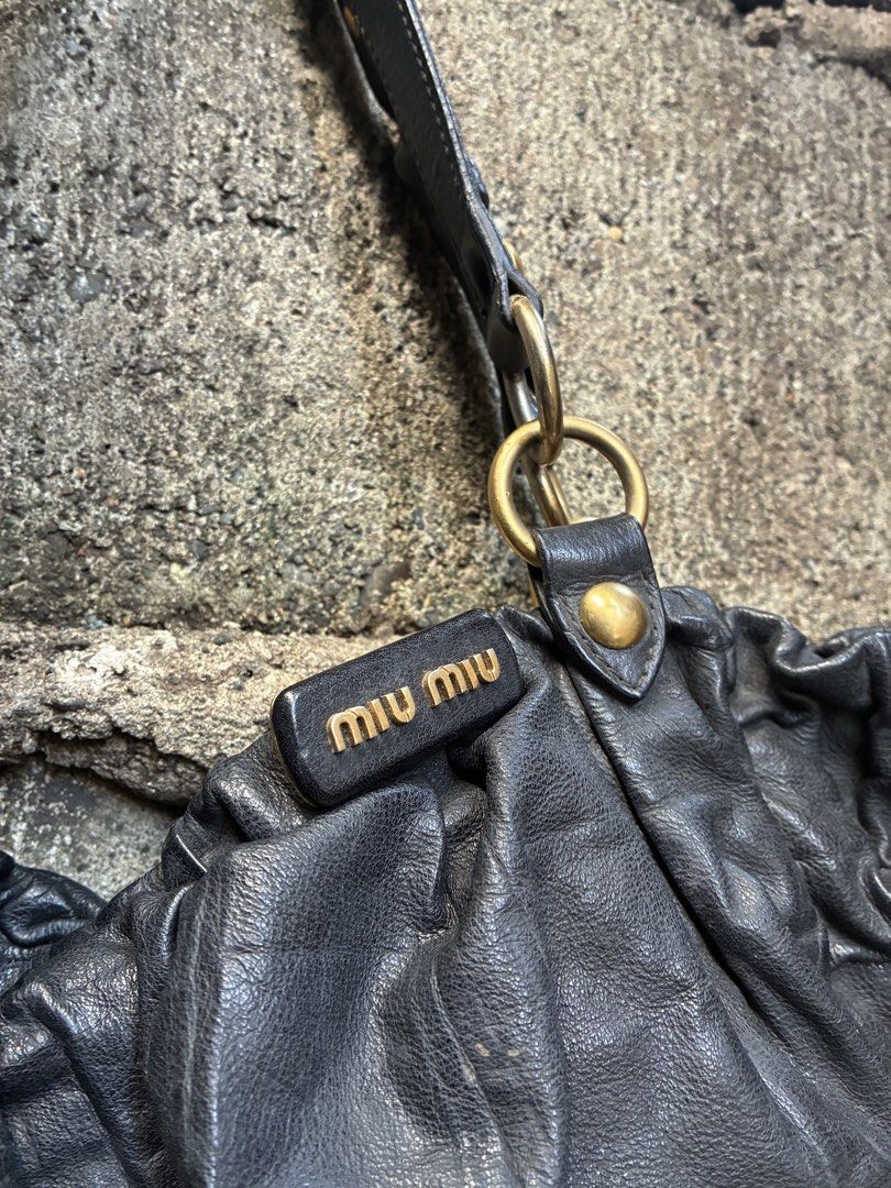 Authentic Miu Miu Black Leather Shoulder Bag (Category: Shoulder Bags) located in Manila. Submitted by assortedgoodsv3 (Listing ID 1470619796, Image 2). Description: - Brand: Miu Miu - Material: Soft black gathered leather with structured vertical panels - Hardware: Premium gold-tone (rings, studs, and zipper pullers) - Straps: Dual comfortable shoulder straps with metal ring attachments - Interior: Black fabric lining with a secure zip pocket an