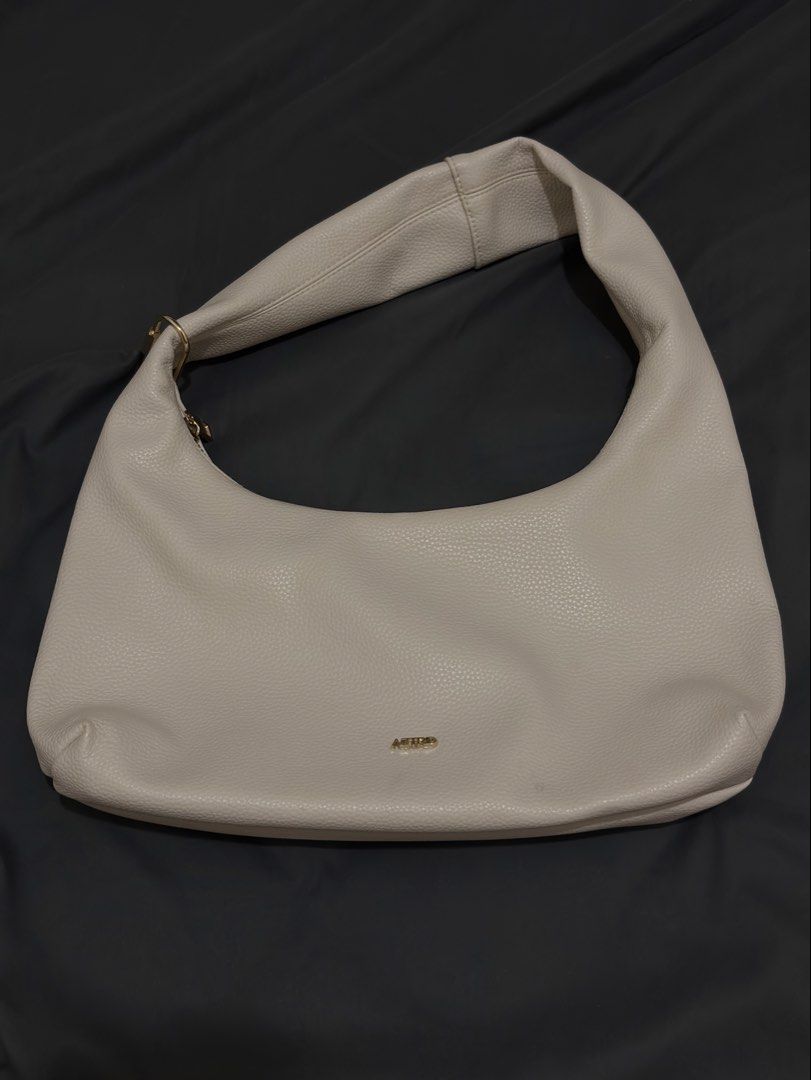 Aztrid Hobo Bag Beige (Small) (Category: Shoulder Bags) located in Manila. Submitted by prelovedbyhaze (Listing ID 1470672333, Image 1). Description: - Color: Creamy beige - Material: Pebbled faux leather with gold-tone hardware - Design: Structured slouchy shape with a secure top zip closure - Strap: Single shoulder strap designed for comfortable daily wear - Interior: Clean and spacious enough for essentials - Style: Minimalist and versatile, e