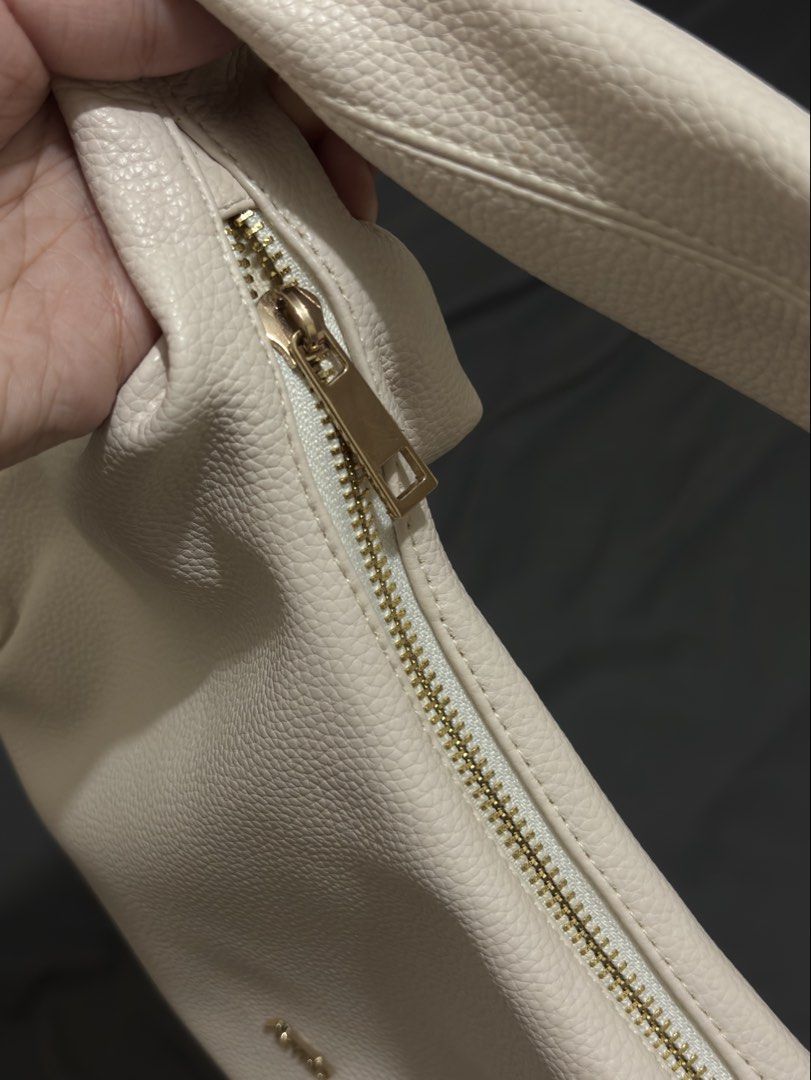 Aztrid Hobo Bag Beige (Small) (Category: Shoulder Bags) located in Manila. Submitted by prelovedbyhaze (Listing ID 1470672333, Image 3). Description: - Color: Creamy beige - Material: Pebbled faux leather with gold-tone hardware - Design: Structured slouchy shape with a secure top zip closure - Strap: Single shoulder strap designed for comfortable daily wear - Interior: Clean and spacious enough for essentials - Style: Minimalist and versatile, e