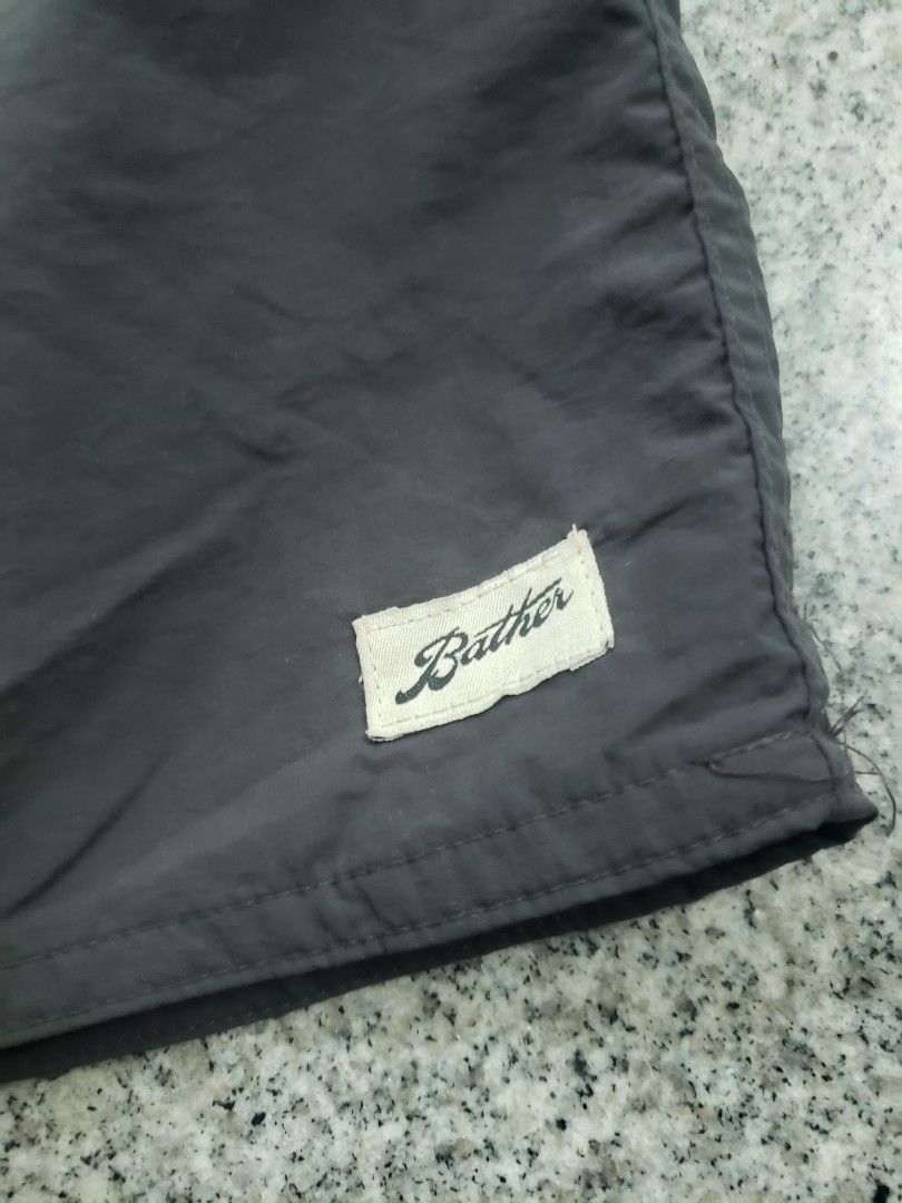 Bather Dark Grey Swim Trunks Size 34 (Category: Swim Trunks & Board Shorts) located in Pagsanghan. Submitted by yuchinz (Listing ID 1470660596, Image 2). Description: - Brand: Bather - Color: Solid dark grey - Size: 34 waist with adjustable drawstring closure - Material: 100% polyester shell, 100% nylon lining - Origin: Made in Canada - Details: Small woven Bather branding patch near the hem - Care: Machine wash cold, hang to dry.