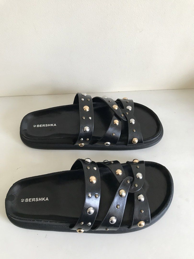 Bershka Black Studded Slide Sandals Size 40 (Category: Flats & Sandals) located in Cainta. Submitted by ukaymama (Listing ID 1470608401, Image 1). Description: - Brand: Bershka - Size: EU 40 - Color: Black with mixed gold and silver-tone metal studs - Style: Slip-on slide sandals with multiple straps - Soles: Flat with textured bottom grip for traction - Condition: Clean footbed and minimal wear on the soles.
