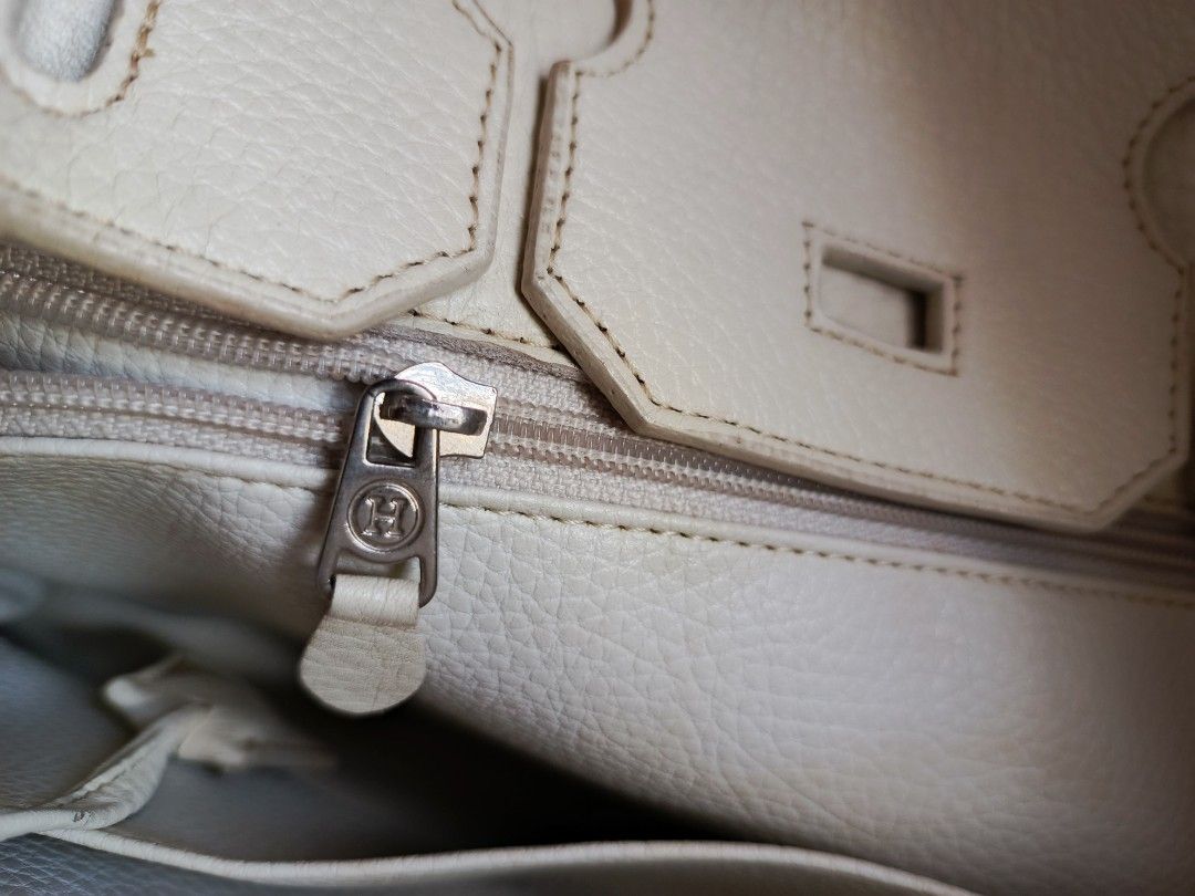 Birkin White Leather Handbag (Category: Luxury Bags & Wallets) located in Marikina City. Submitted by wisebuytoo (Listing ID 1470594574, Image 3). Description: With FREE one woven Handbag - Color & Material: Cream white grained leather - Hardware: Silver-tone with minor wear - Closure: Classic front turn-lock - Handles: Double top handles for easy carry - Interior: Lined with a zipper pocket and signature 'H' zipper pull - Protection: Metal feet 