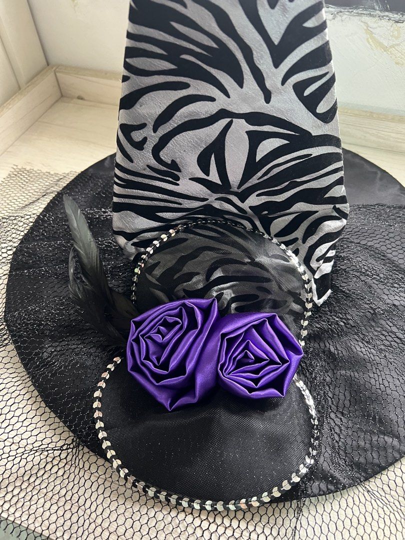 Black and silver zebra witch hat with purple roses (Category: Caps & Hats) located in Makati City. Submitted by esila.essentials (Listing ID 1470668924, Image 3). Description: FOR RENT - Design: Black and silver zebra print witch hat - Brim & Netting: Large black brim with layered black netting underneath - Details: Decorated with a sparkly sequin trim border and black feathers - Accents: Two vibrant bright purple satin roses near the front - Per