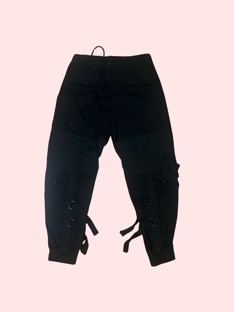 Black Cargo Pants (Category: Other Bottoms) located in Pasig City. Submitted by kia.sell (Listing ID 1470632281, Image 2). Description: - Brand: Bershka (100% Authentic) - Style: Tactical techwear cargo jogger pants - Color: Matte Black with red accent stitching - Design Details: Flap cargo pockets with toggle drawstrings, red zippered front slash pockets, elasticized drawstring waistband, and ribbed jogger cuffs. - Condition: Excellent pre-loved