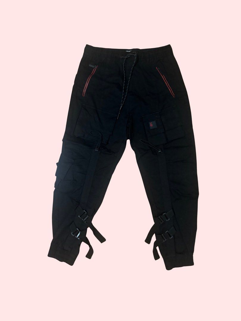 Black Cargo Pants (Category: Other Bottoms) located in Pasig City. Submitted by kia.sell (Listing ID 1470632281, Image 1). Description: - Brand: Bershka (100% Authentic) - Style: Tactical techwear cargo jogger pants - Color: Matte Black with red accent stitching - Design Details: Flap cargo pockets with toggle drawstrings, red zippered front slash pockets, elasticized drawstring waistband, and ribbed jogger cuffs. - Condition: Excellent pre-loved